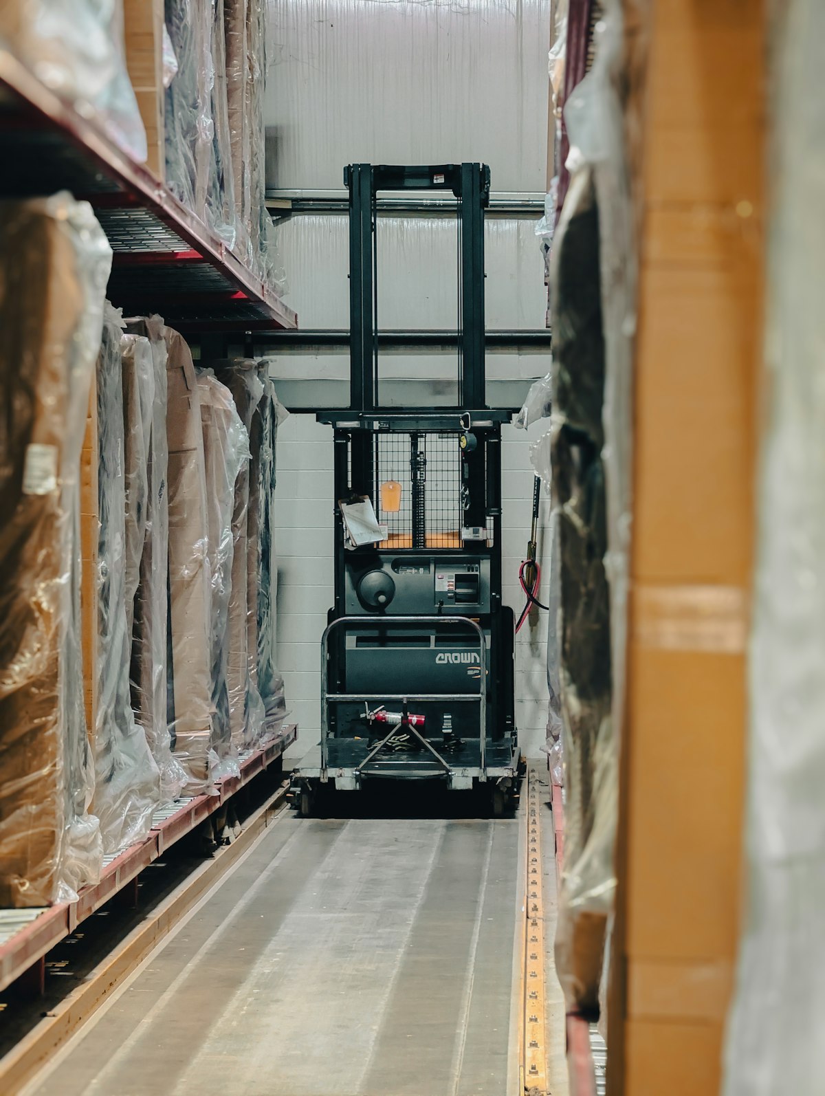 A forklift between stacks of wrapped stock in a warehouse